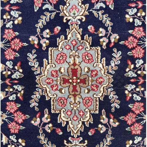 64 - A Persian Kerman rug with central medallion and floral sprays within a red border, on a blue ground,... 