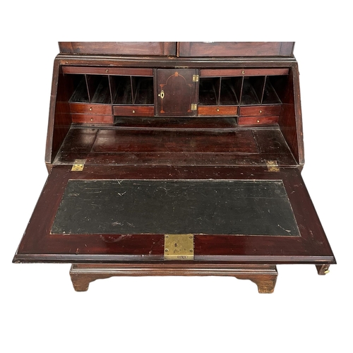 667 - An early 19th century mahogany bureau bookcase, the pair of shaped glazed doors enclosing a shelved ... 