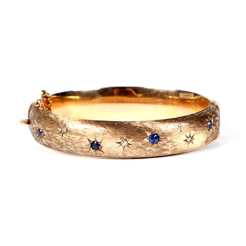 484 - A 9ct gold diamond and sapphire set hinged bangle, 27.2g.