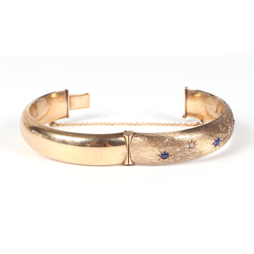 484 - A 9ct gold diamond and sapphire set hinged bangle, 27.2g.