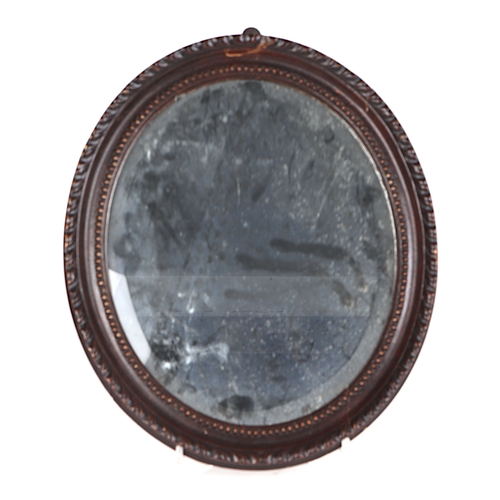 711 - An early 19th century carved oak oval wall mirror with bevelled plate, 36cms high; together with ano... 