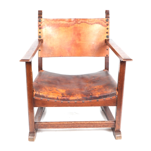 750 - An Arts & Crafts inspired stained beech child's armchair with leather back and seat.