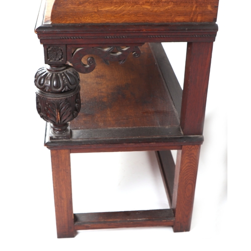 594 - An oak two-tier side table with carved supports, 90cms wide.