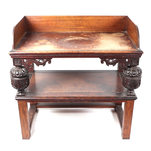 594 - An oak two-tier side table with carved supports, 90cms wide.