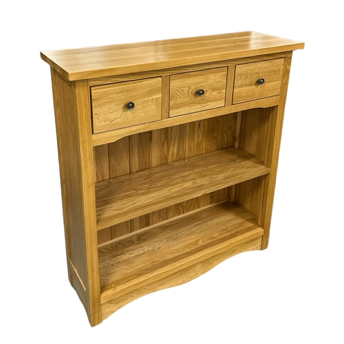 714 - A modern oak side cabinet with three frieze drawers above an open two-tier bookshelf, 90cms wide; to... 