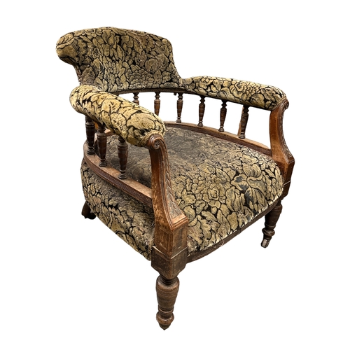 577 - A Victorian upholstered tub armchair with carved show wood arms and turned front legs.