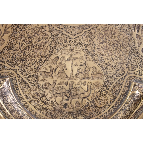 501 - A Persian brass tray of shaped form decorated with figures within panels and foliate scrolls, 57cms ... 