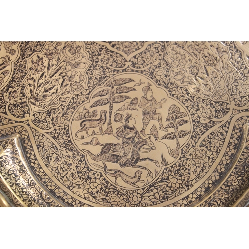 501 - A Persian brass tray of shaped form decorated with figures within panels and foliate scrolls, 57cms ... 