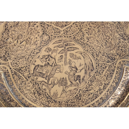 501 - A Persian brass tray of shaped form decorated with figures within panels and foliate scrolls, 57cms ... 