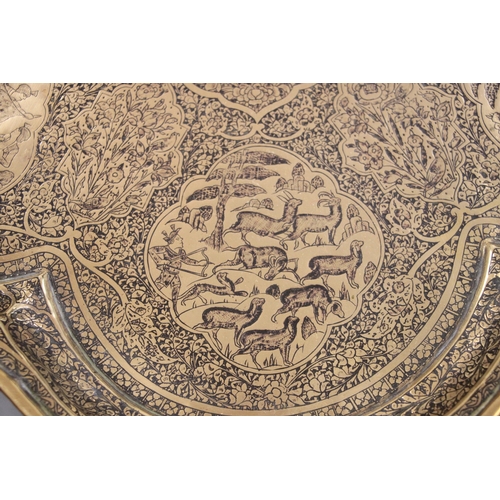 501 - A Persian brass tray of shaped form decorated with figures within panels and foliate scrolls, 57cms ... 