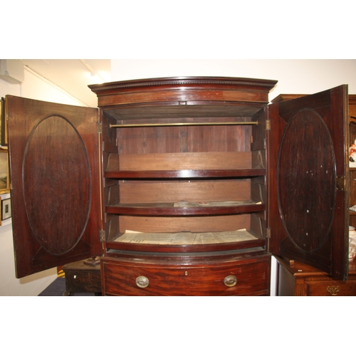 727 - A George III mahogany bowfront linen press with dentil cornice above a pair of panelled doors enclos... 