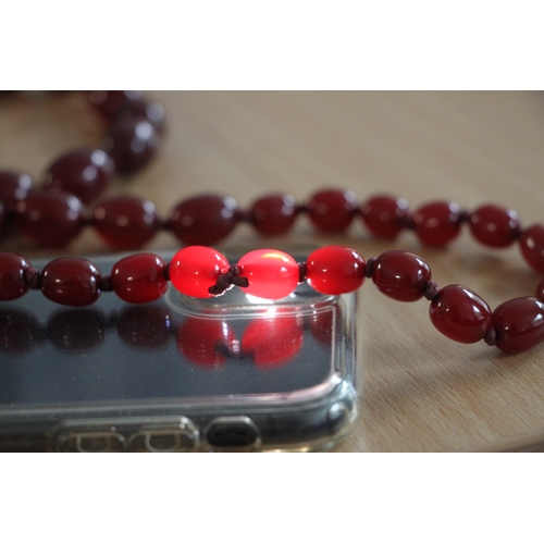 480 - A graduated set of cherry amber Bakelite type beads, the largest bead 3cms long.