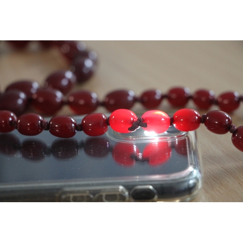 480 - A graduated set of cherry amber Bakelite type beads, the largest bead 3cms long.