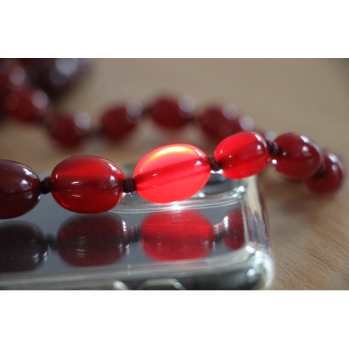 480 - A graduated set of cherry amber Bakelite type beads, the largest bead 3cms long.