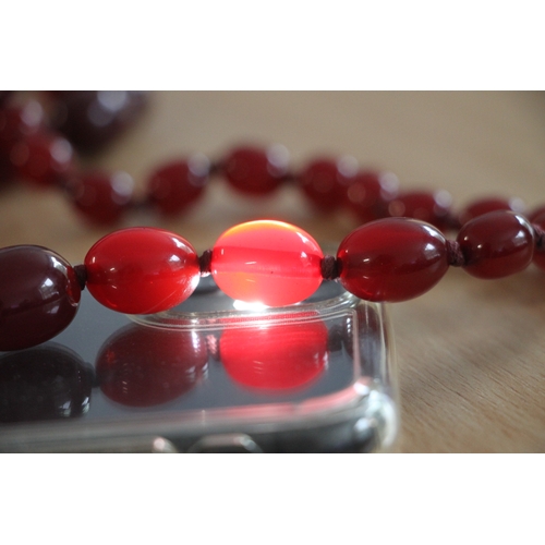 480 - A graduated set of cherry amber Bakelite type beads, the largest bead 3cms long.