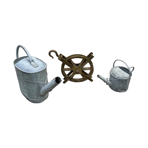 11 - Two galvanised watering cans, together with a cast iron pulley (3).