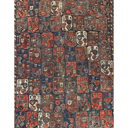 125 - A Persian Bakhtiar rug decorated with a multitude of medallions, on a red ground, 165 by 200cms.