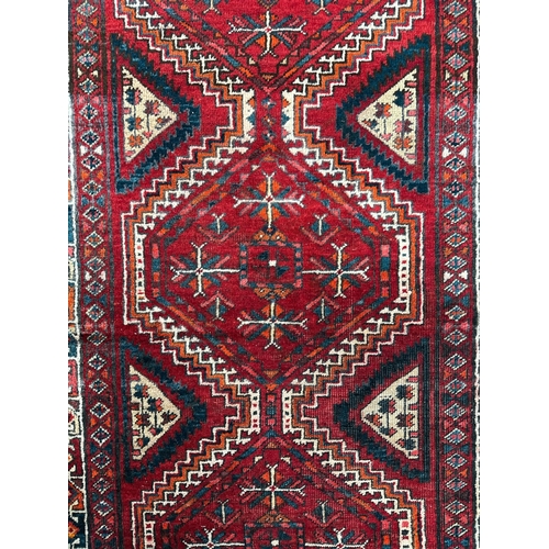 147 - A Persian hand knotted woollen Hamadan runner with three central geometric guls within geometric fie... 