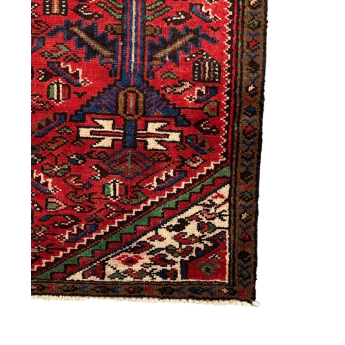 148 - A Persian hand knotted woollen Hamadan rug with central medallion within floral borders, on a red gr... 