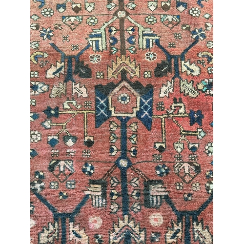 157 - A Persian Hamadan hand knotted woollen rug with repeating stylised design, on a red ground, 105 by 1... 