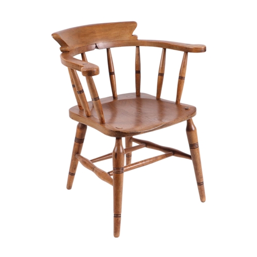 828 - A late Victorian oak smoker's bow armchair with spindle back, solid seat and turned front legs joine... 