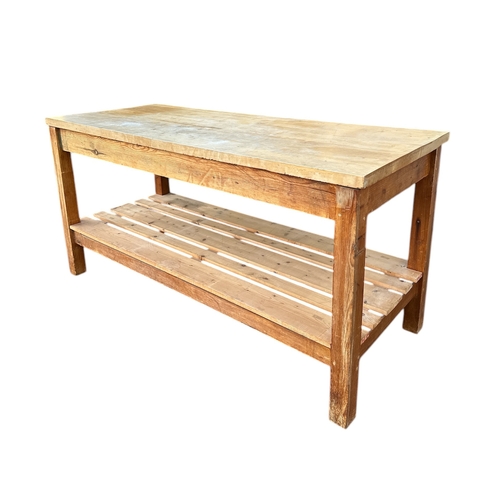 816 - A large pine kitchen table, the rectangular top above a planked under-tier, on square legs, 183cms w... 