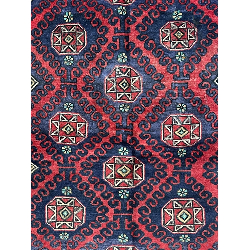 146 - A Persian Baluch hand knotted rug with repeat geometric squares within a double wave border, on a re... 