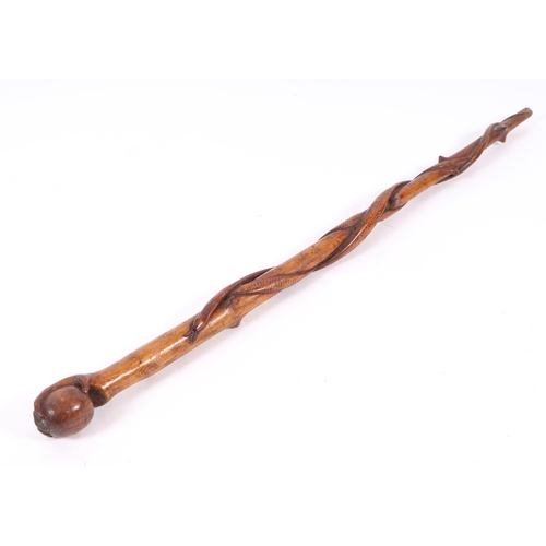 1655 - A folk art walking stick, the shaft carved with entwined snakes, the terminal in the form of a hand ... 