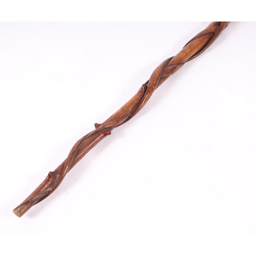 1655 - A folk art walking stick, the shaft carved with entwined snakes, the terminal in the form of a hand ... 