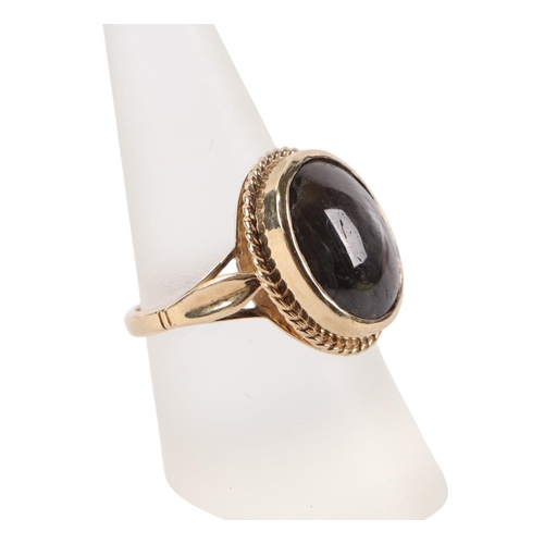 518 - A 9ct gold ring set with an oval grey hardstone / grey sapphire cabochon, approx UK size O, 7g.