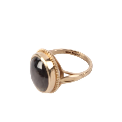 518 - A 9ct gold ring set with an oval grey hardstone / grey sapphire cabochon, approx UK size O, 7g.