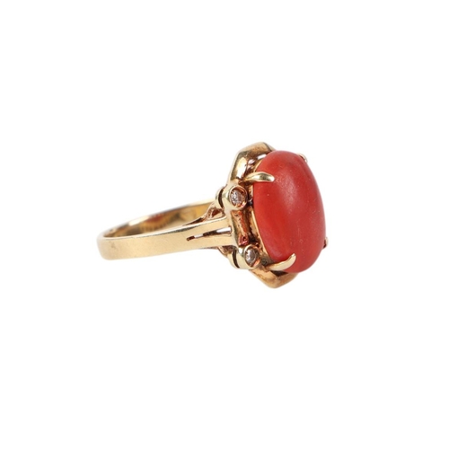 527 - A 14ct gold ring set with a central coral cabochon flanked by four diamonds, approx UK size O, 5.4g.