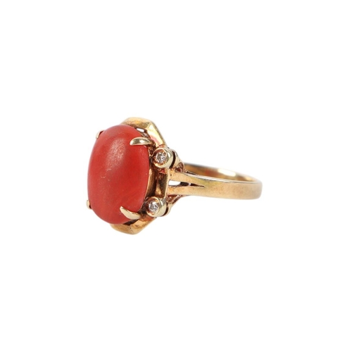 527 - A 14ct gold ring set with a central coral cabochon flanked by four diamonds, approx UK size O, 5.4g.