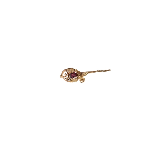 543 - A Victorian yellow metal stick pin of strap and buckle design, set with a single garnet, boxed.