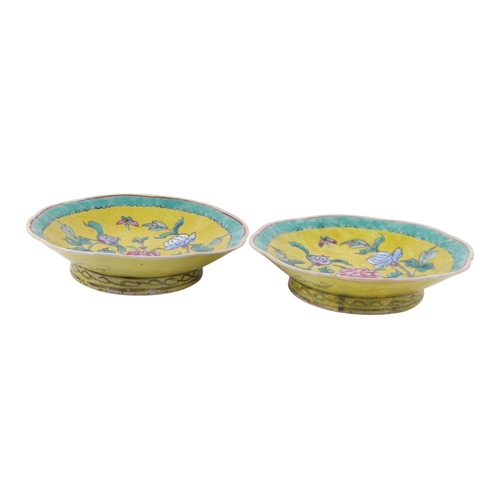 594 - A pair of Chinese famille vert shaped footed bowls decorated with flowers on a yellow ground within ... 