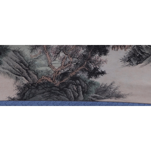 612 - A Chinese scroll depicting a mountainous landscape scene with calligraphy, 62 by 127cms.