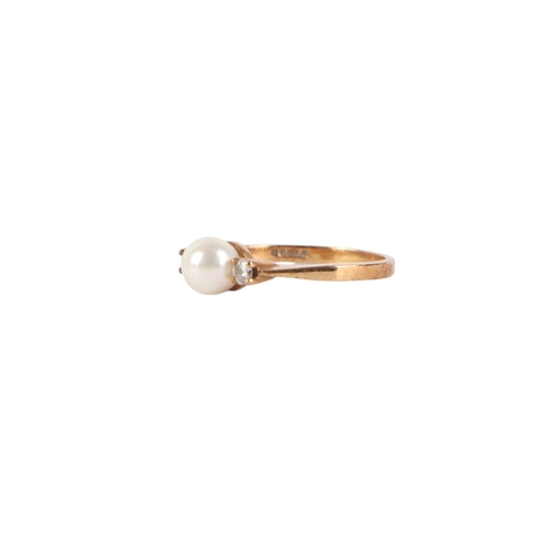 540 - A 9ct gold ring set with a central pearl flanked by two diamonds, approx UK size M, 2g.