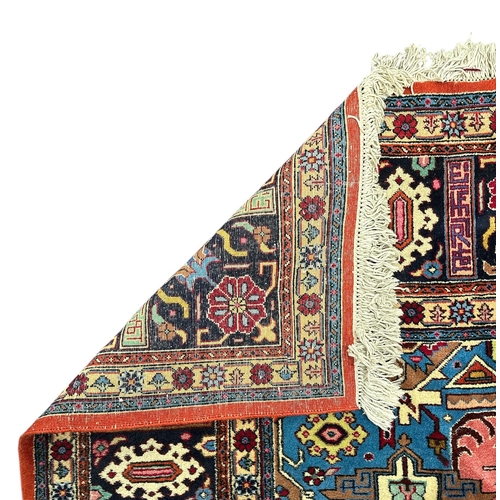 135 - A Persian Heriz woollen hand knotted carpet with stylised floral central medallion on a pink ground ... 