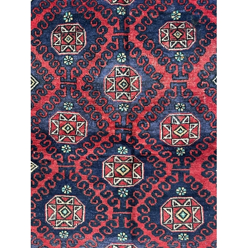 140 - A Persian Baluch hand knotted rug with repeat geometric squares within a double wave border, on a re... 