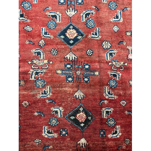 155 - A Persian Hamedan woollen hand knotted rug with geometric design and figures, on a red ground, 143 b... 