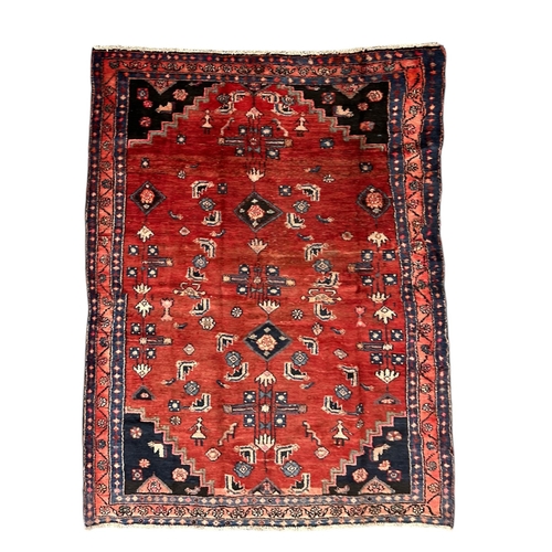 155 - A Persian Hamedan woollen hand knotted rug with geometric design and figures, on a red ground, 143 b... 