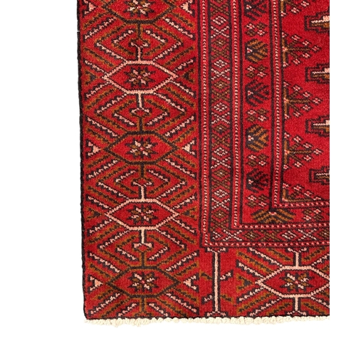 158 - A Persian Turkoman woollen hand knotted rug with repeating geometric design, on a red ground, 180 by... 