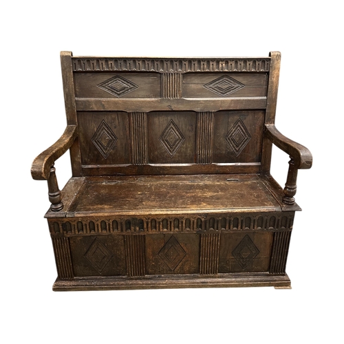 908 - A 19th century oak box settle with carved three-panelled back, scroll arms, the box section with thr... 