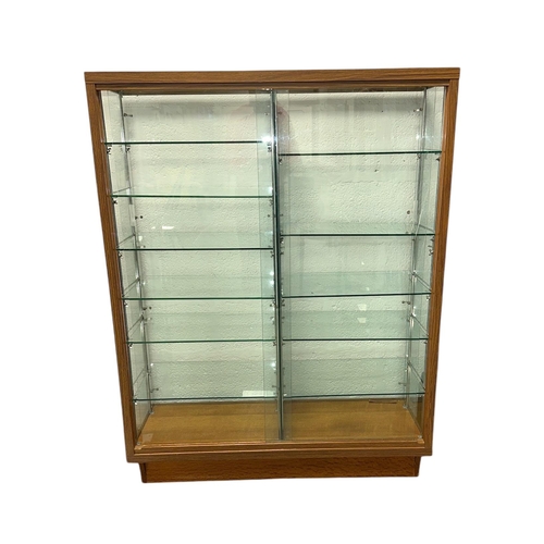 910 - A mid 20th century glass shop display cabinet with sliding doors, 108cms wide.