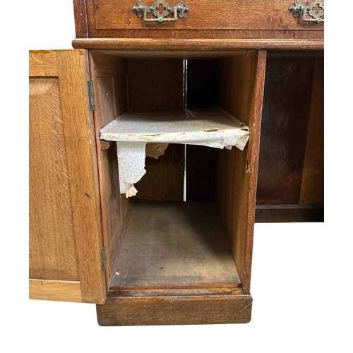 907 - A late 19th / early 20th century oak pedestal desk with an arrangement of drawers and cupboards, on ... 