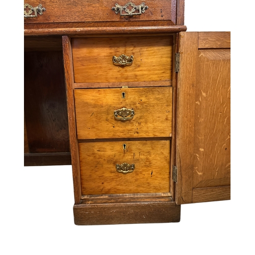 907 - A late 19th / early 20th century oak pedestal desk with an arrangement of drawers and cupboards, on ... 