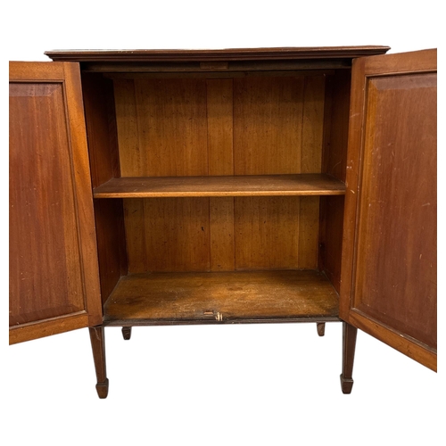 1034 - An Edwardian mahogany cupboard, the pair of panelled doors enclosing a shelved interior, on square t... 