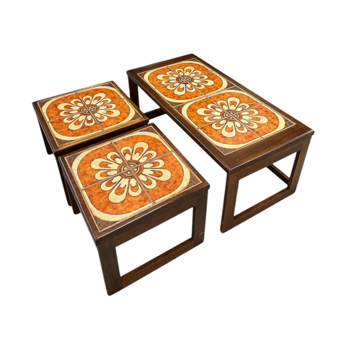 1093 - A mid 20th century design nest of three tile topped tables, the largest 96cms wide; together with a ... 