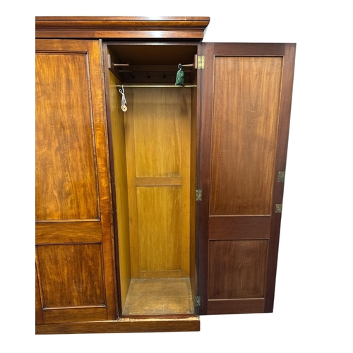 1112 - A Victorian mahogany triple wardrobe. the panelled door enclosing hanging space, linen slides and tw... 