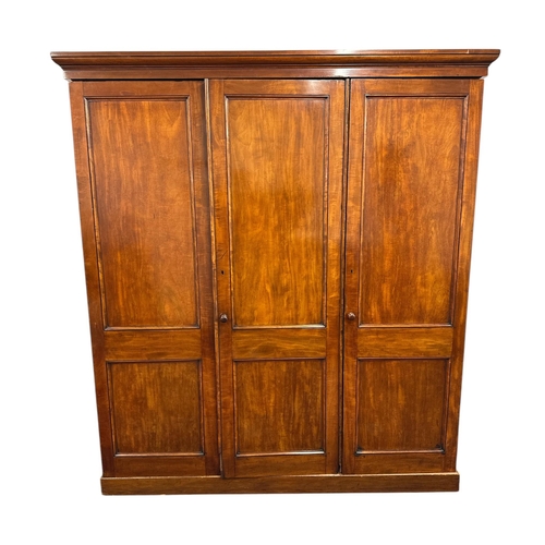 1112 - A Victorian mahogany triple wardrobe. the panelled door enclosing hanging space, linen slides and tw... 